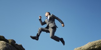Man in suit jumping between towering rocks