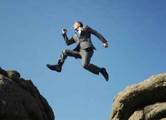 Man in suit jumping between towering rocks